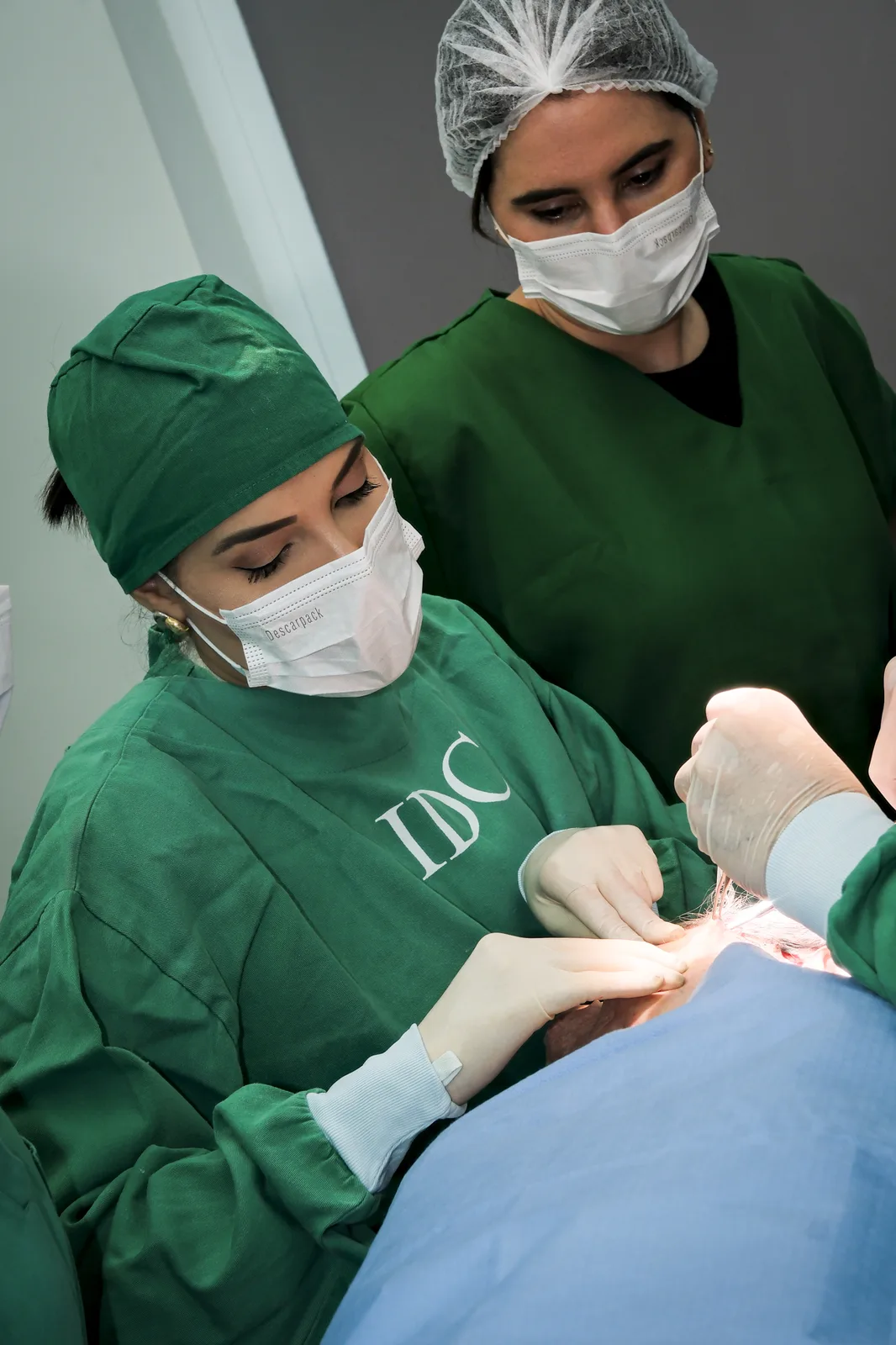 Duas alunas do IDC operando sob supervisão em sala cirúrgica